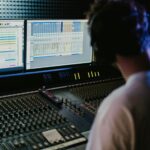 Sound engineer working with mixing console and monitors in a modern recording studio.