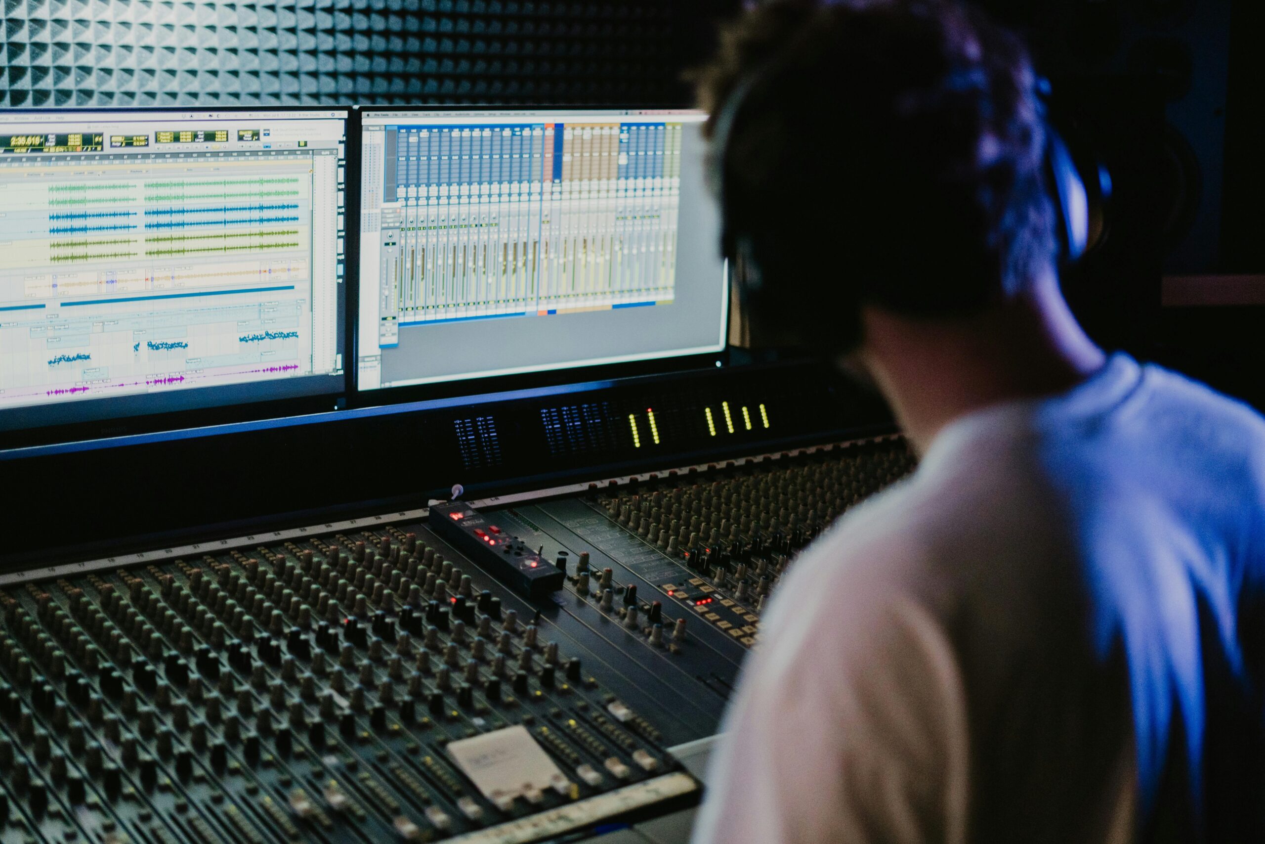 Sound engineer working with mixing console and monitors in a modern recording studio.